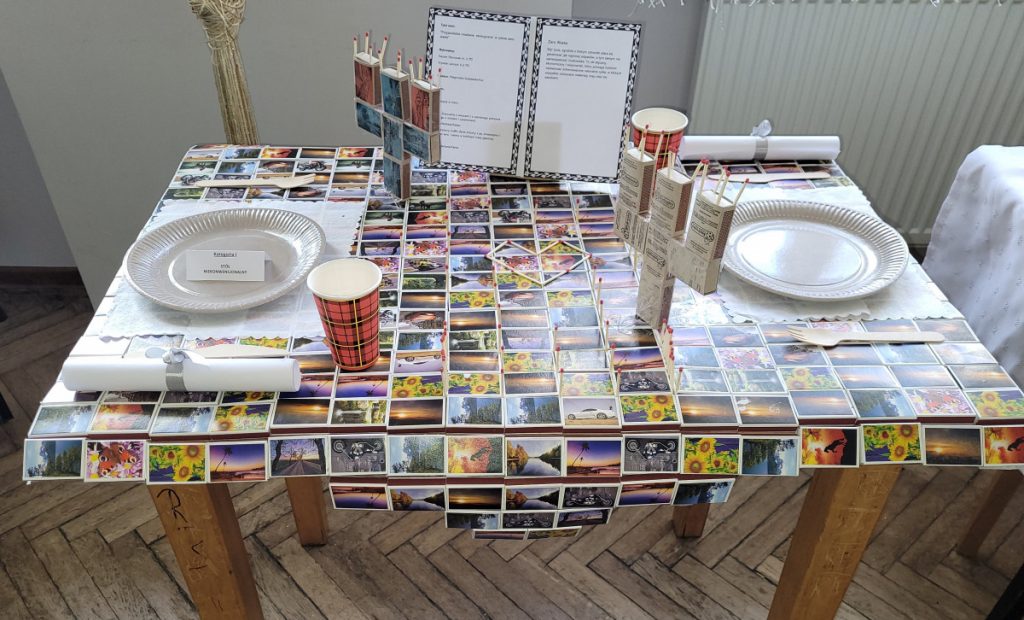 Zdjęcie - Cały stół dla dwóch osób został przygotowany z małych kolorowych pudełek po zapałkach. Nakryciem dla gości są talerze i sztućce biodegradowalne. Dwa świecznik na trzy świeczki zostały wykonane z pudełek po zapałkach.